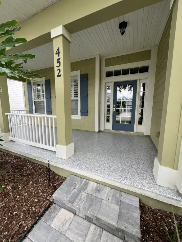 Beautifully painted house exterior with fresh coating, featuring a welcoming porch, white railing, and vibrant green walls with blue accents.