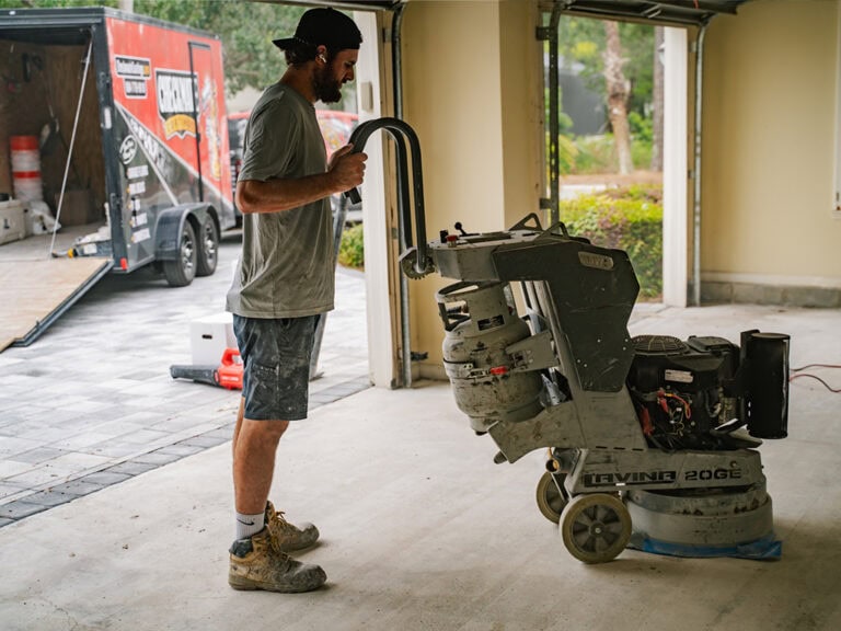 Efficient concrete grinding process by professional at Checkmate Coatings, ensuring smooth and durable surfaces with high-quality equipment for residential and commercial flooring projects.