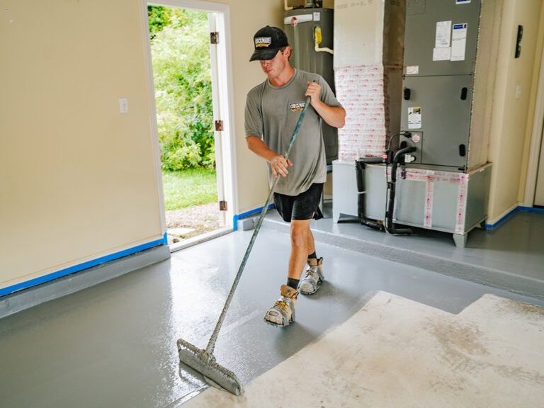 Smooth epoxy flooring being applied in a residential space by a professional from Checkmate Coatings, ensuring durable and high-quality surfaces.