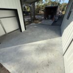 Uncoated garage floor with a clean, smooth surface and a vehicle trailer parked outside.