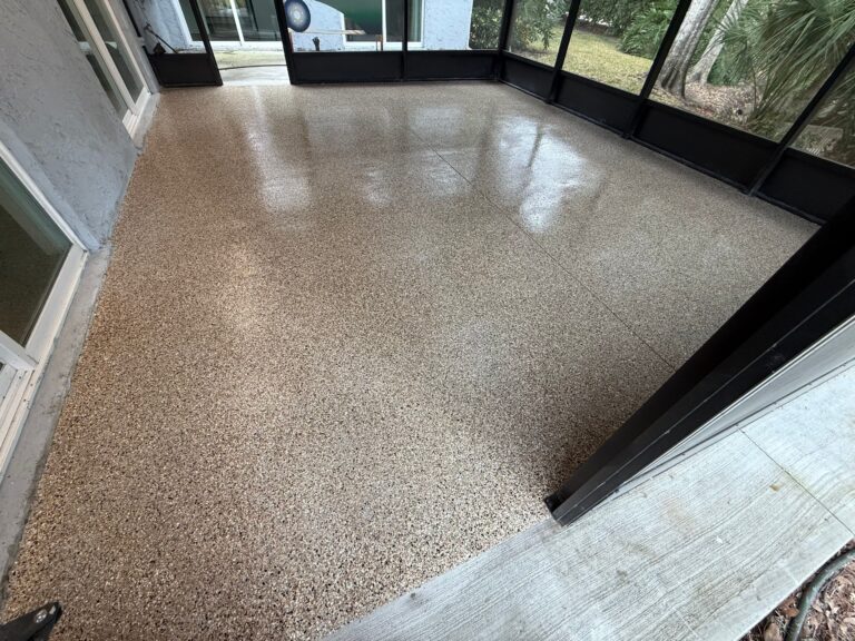 Back patio with newly coated, textured concrete floor in neutral tones, surrounded by screened enclosure and outdoor scenery.