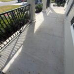 Front porch with light-colored concrete surface and black metal railing.