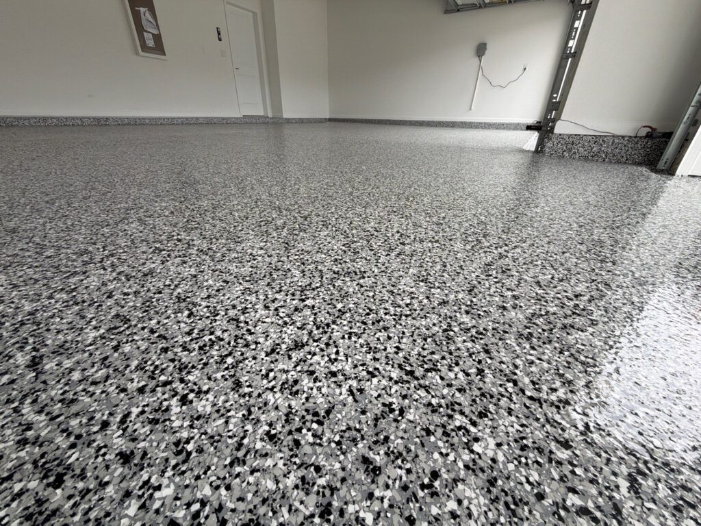 Polished polyaspartic garage floor with speckled gray and black finish in a modern residential garage.