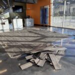 Damaged flooring at Quick Lane Tire & Auto Center, Murray Ford of Kingsland, with scattered wood planks and a partially removed floor section.