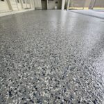 Close-up of a newly coated concrete pool deck with a stonewash finish, showcasing a speckled gray and black texture.