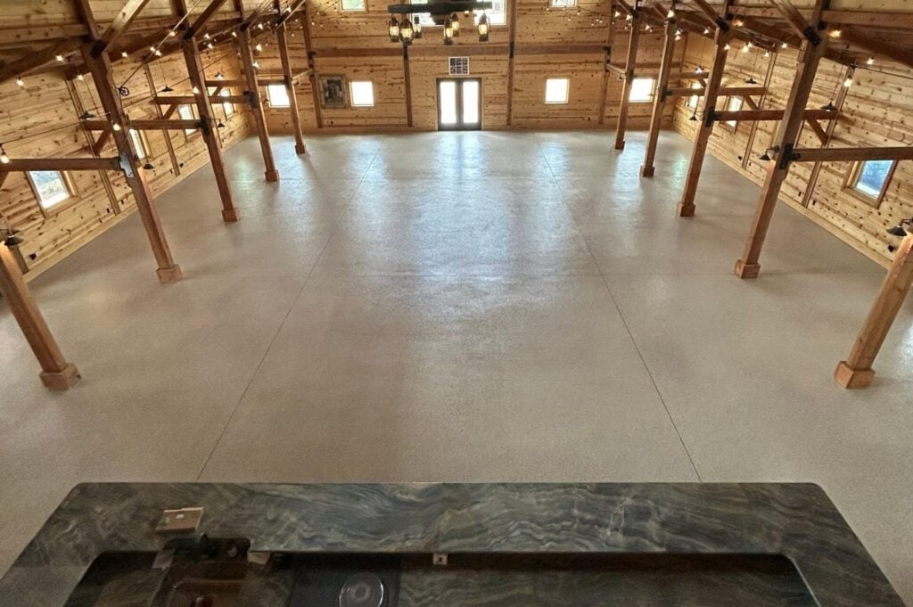 Spacious indoor area with polished concrete floor and wooden beams, suitable for commercial or recreational use.