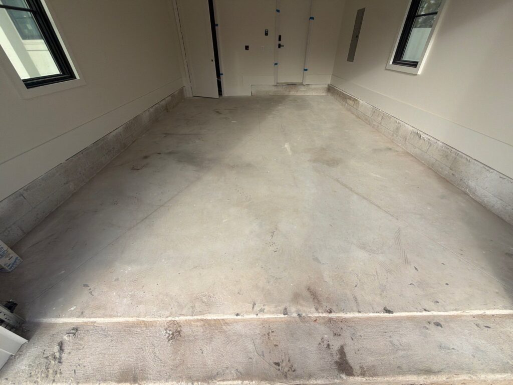 Empty garage floor with concrete surface and baseboard, ready for coating or finishing.