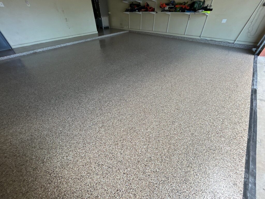 Garage floor with durable, decorative polyaspartic coating by Checkmate Coatings, featuring a smooth, polished finish in Wombat color.