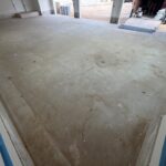 Unfinished garage floor with concrete surface, ready for coating, in a residential garage space.