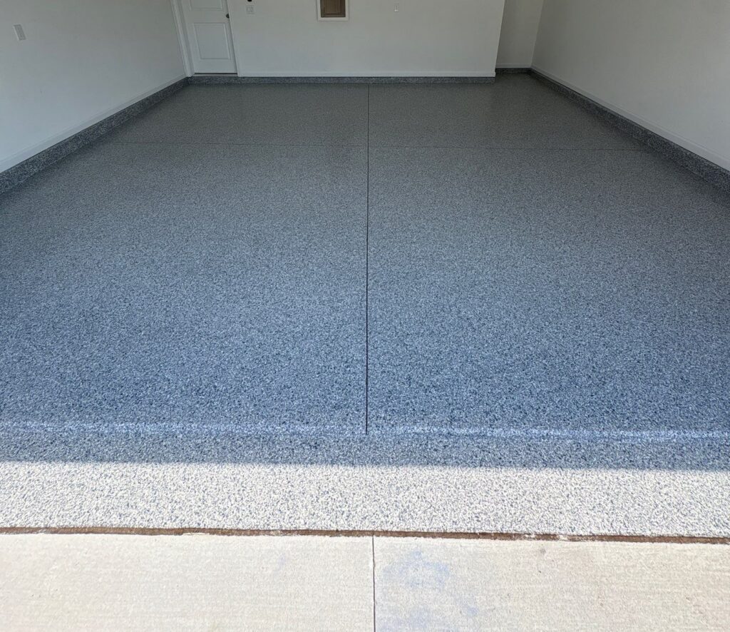 Garage floor coated with durable epoxy finish, showcasing a smooth, speckled gray surface for enhanced durability and aesthetic appeal.